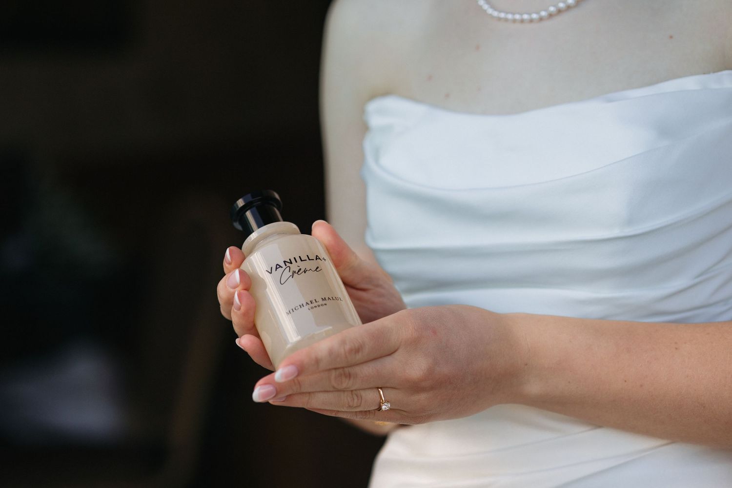 Bride in white strapless gown holding Vanilla Creme perfume bottle by Michael Malul London.