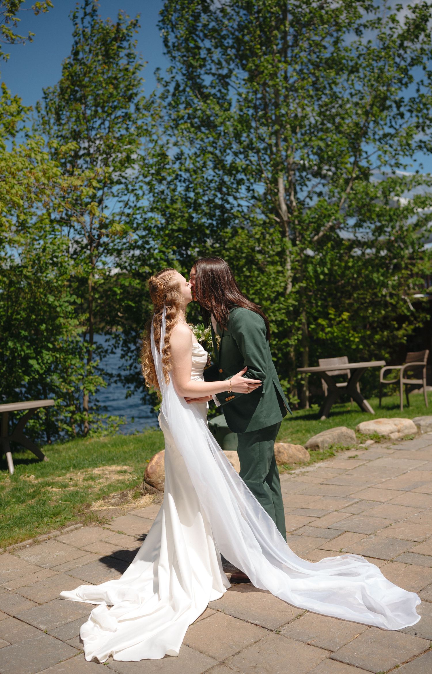 Bride and groom sharing a kiss in a lush garden setting, with the bride in a flowing white gown and veil.