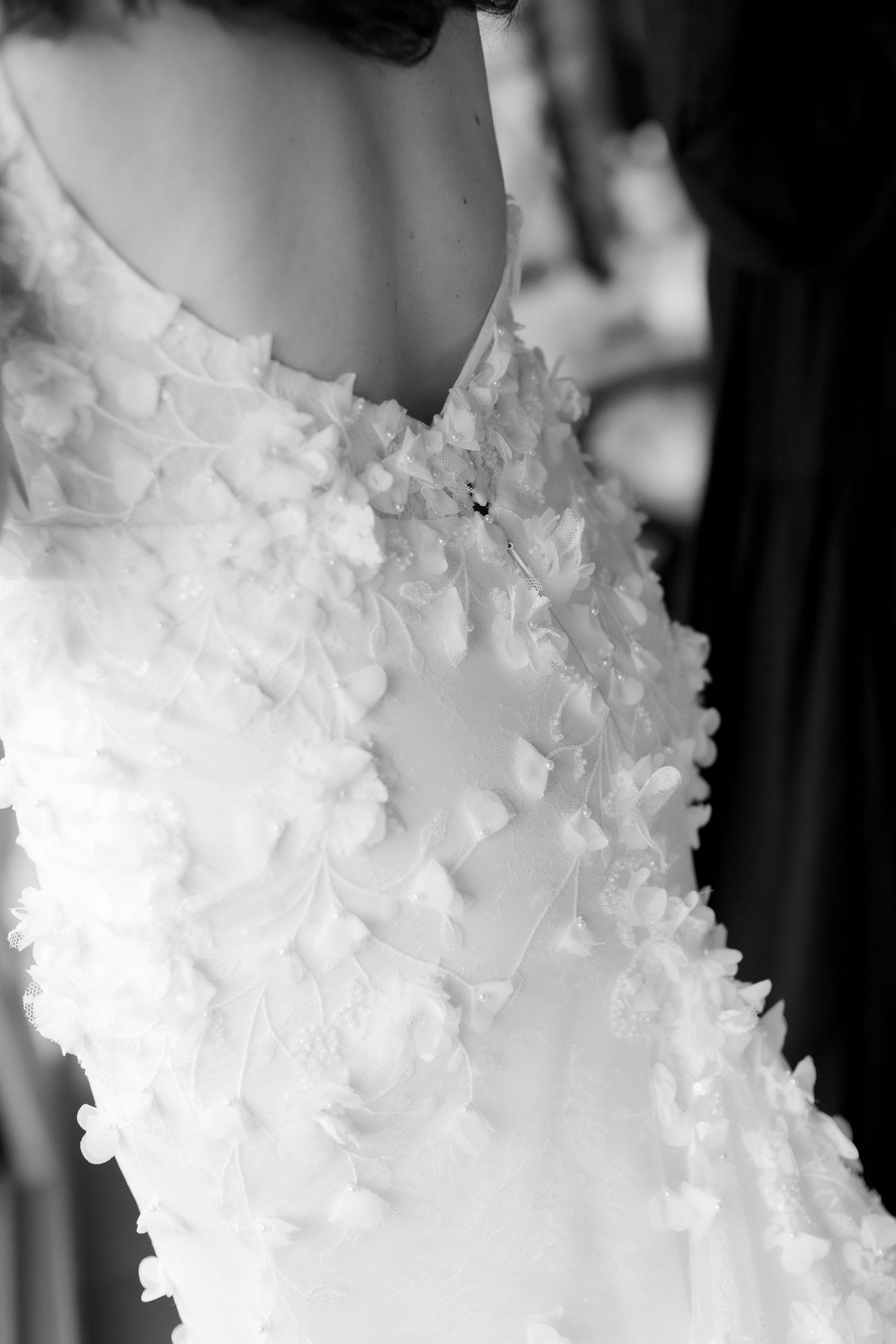Close-up of a white floral applique wedding dress detail in black and white photography.