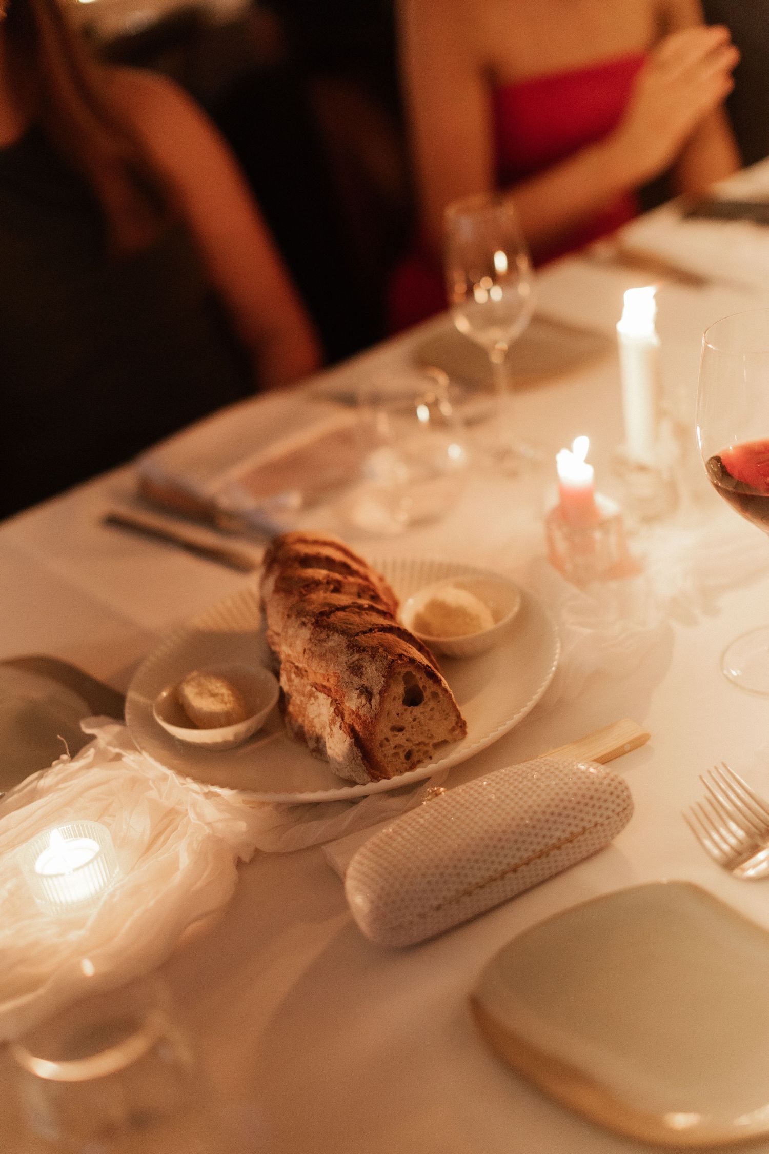 Candlelit wedding reception dinner table with sliced artisan bread and dipping sauces.