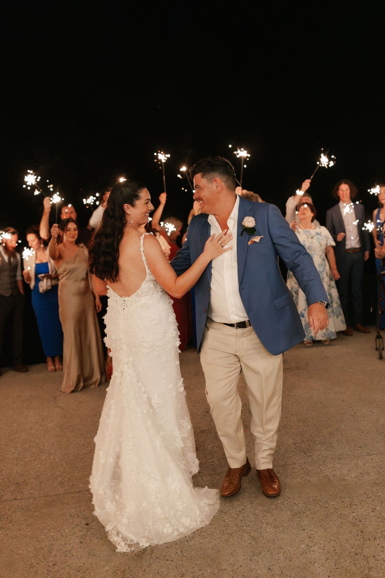 Bride and groom share a joyful moment during a sparkler send-off at their outdoor nighttime wedding reception.
