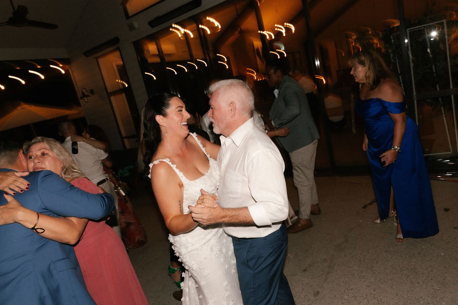 Bride and groom share first dance at outdoor wedding reception, surrounded by guests in formal attire.