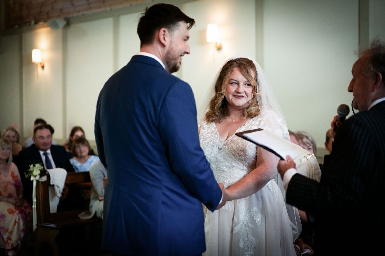 Bride and groom exchanging vows at a church wedding ceremony, smiling joyfully while holding hands.