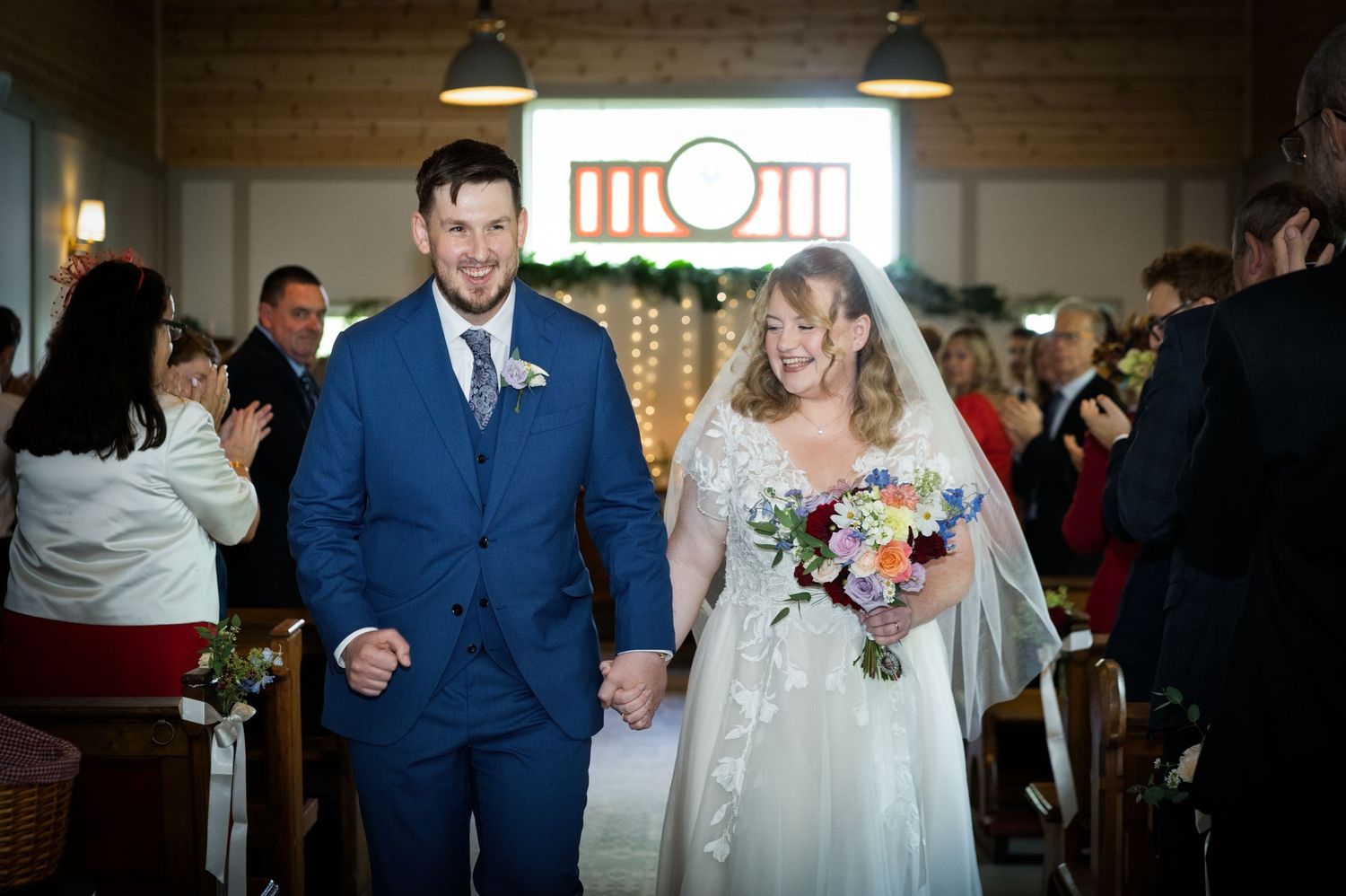 Bride and groom walk joyfully down the aisle hand in hand after their wedding ceremony.