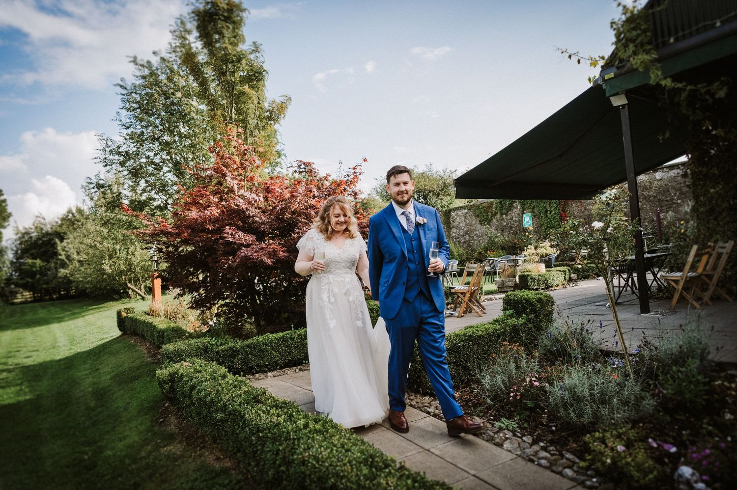 Happy bride and groom stroll through a lush garden venue on their wedding day.