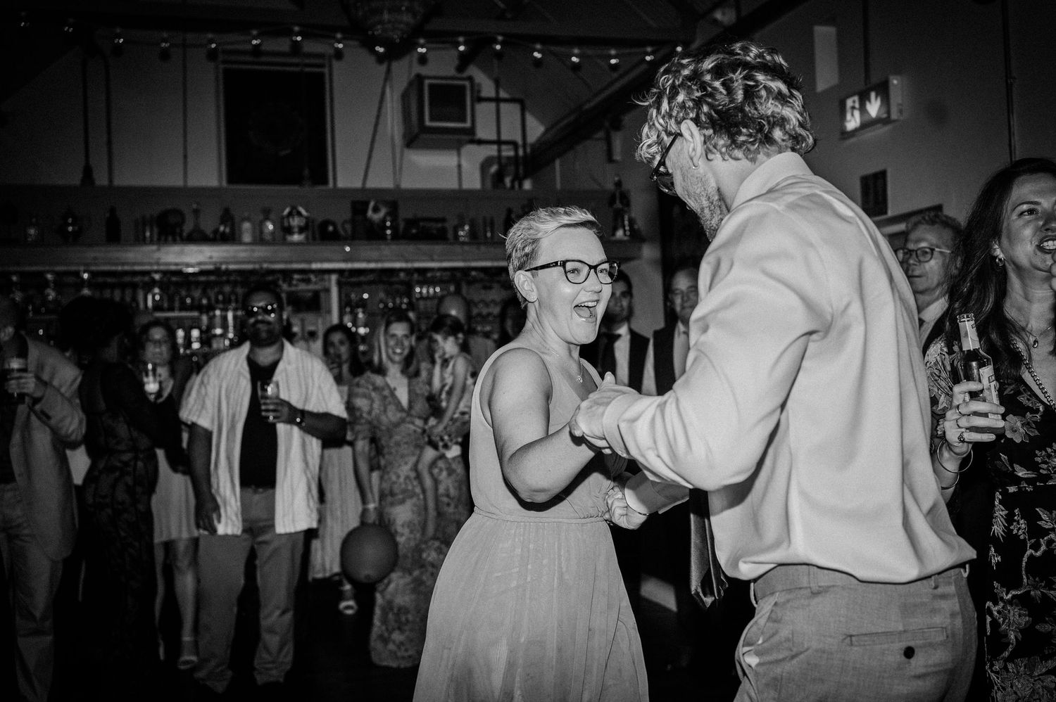 Wedding guests dancing together on the dance floor at a lively evening reception.