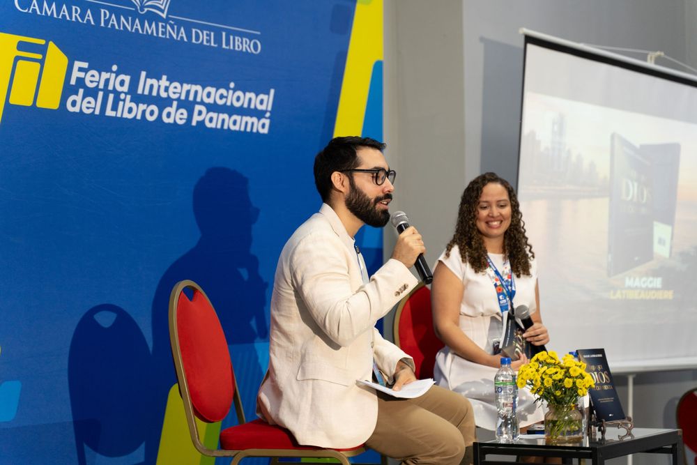 Two speakers present at the Feria Internacional del Libro de Panama, a man with microphone and woman seated at a table.