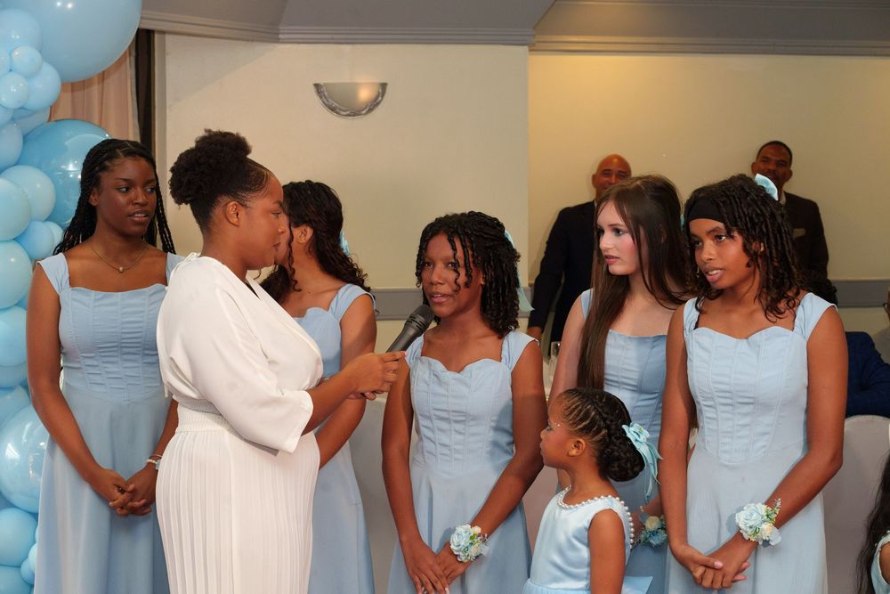 Bridesmaids in light blue dresses gather at a wedding ceremony with balloon decorations.