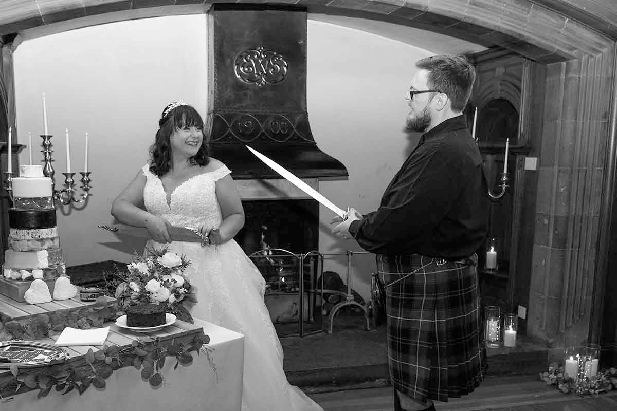 The groom uses a sword to cut the cake at his wedding- held at Dalston Hall- wedding venue