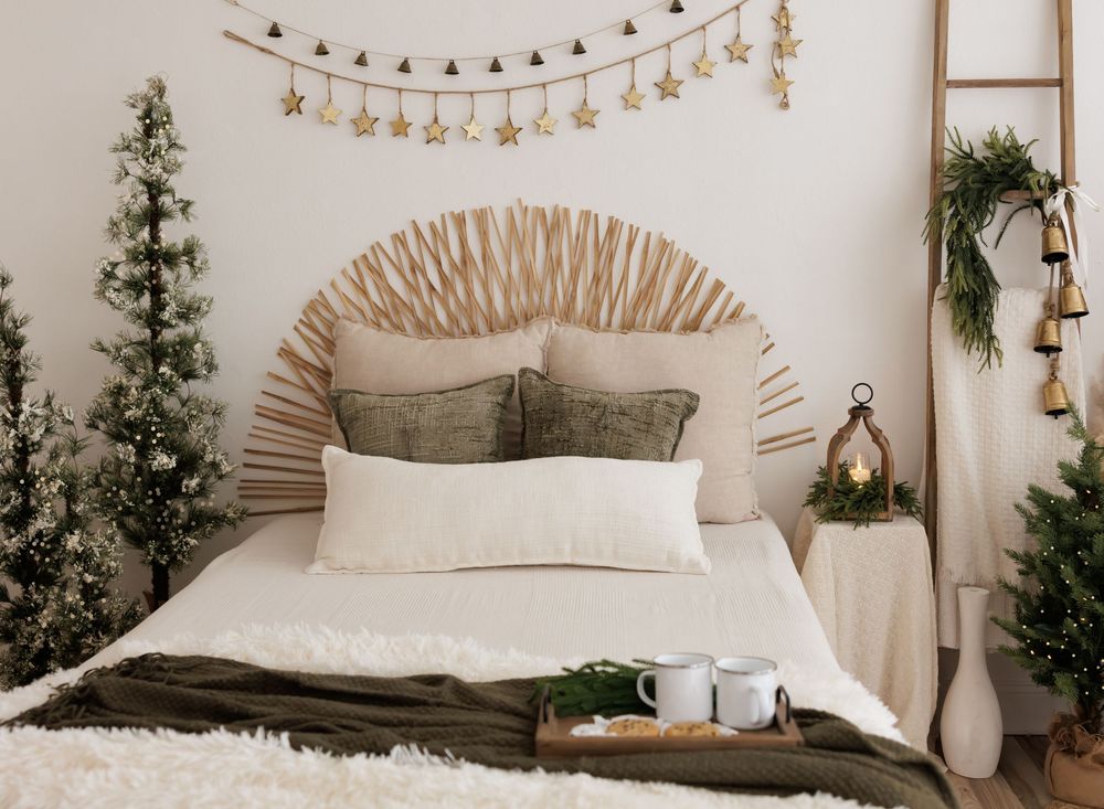 Cozy boho bedroom with rattan headboard, Christmas trees, star garland, and neutral bedding in festive holiday decor.