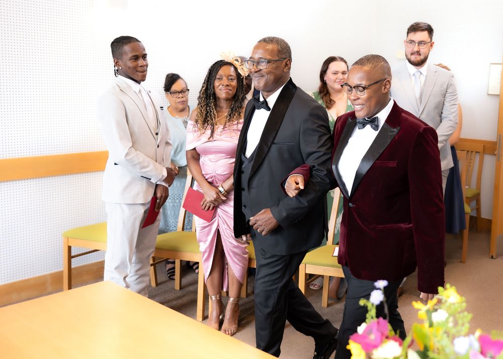 Wedding guests in formal attire walk through a ceremony venue with flowers on the table.
