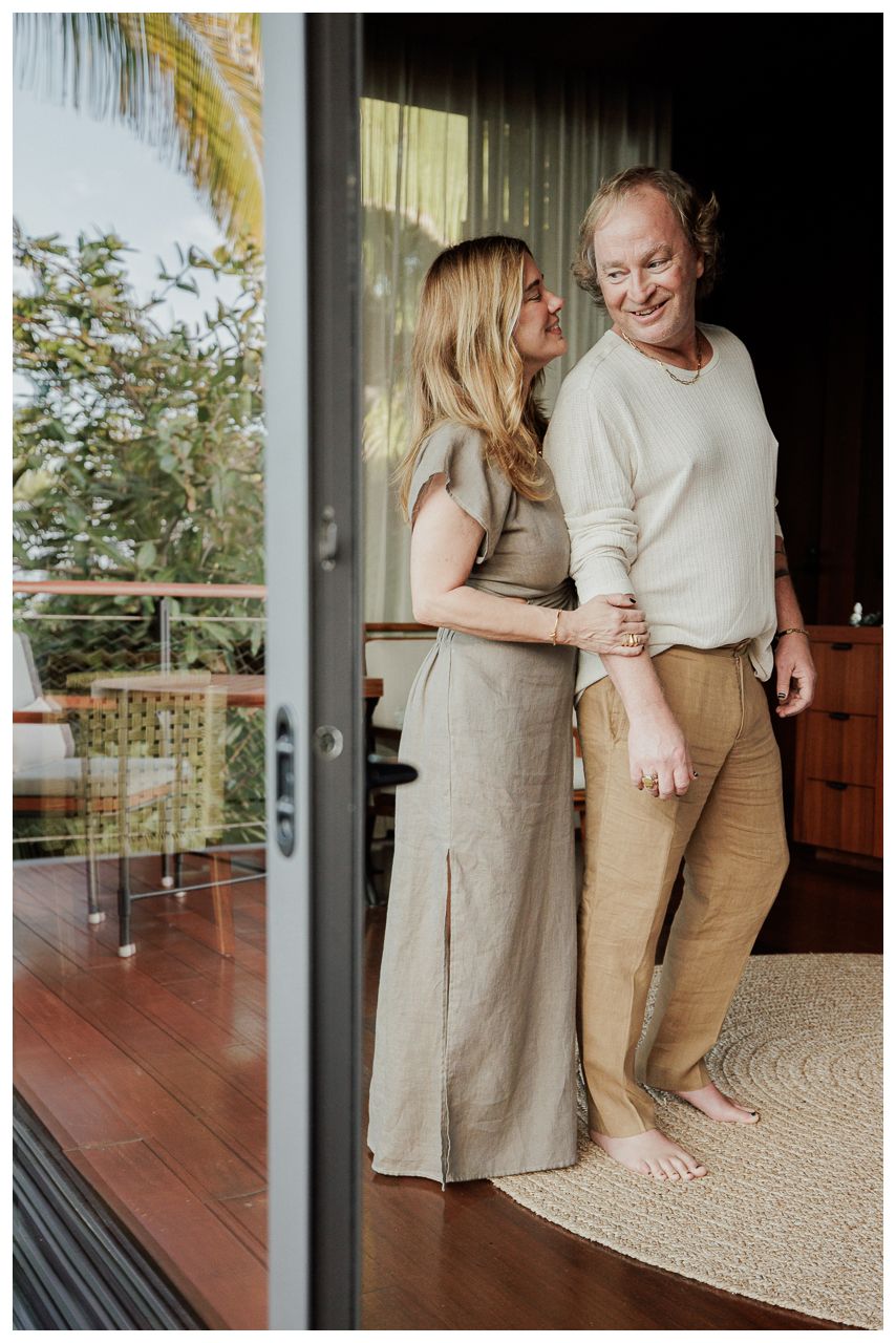 Luxury Couple Photography at One & Only Mandarina Resort featuring a smiling couple embracing in a modern villa doorway.