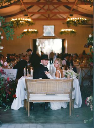 Vintage cane loveseat displayed at an elegant indoor wedding reception with chandeliers and floral arrangements.