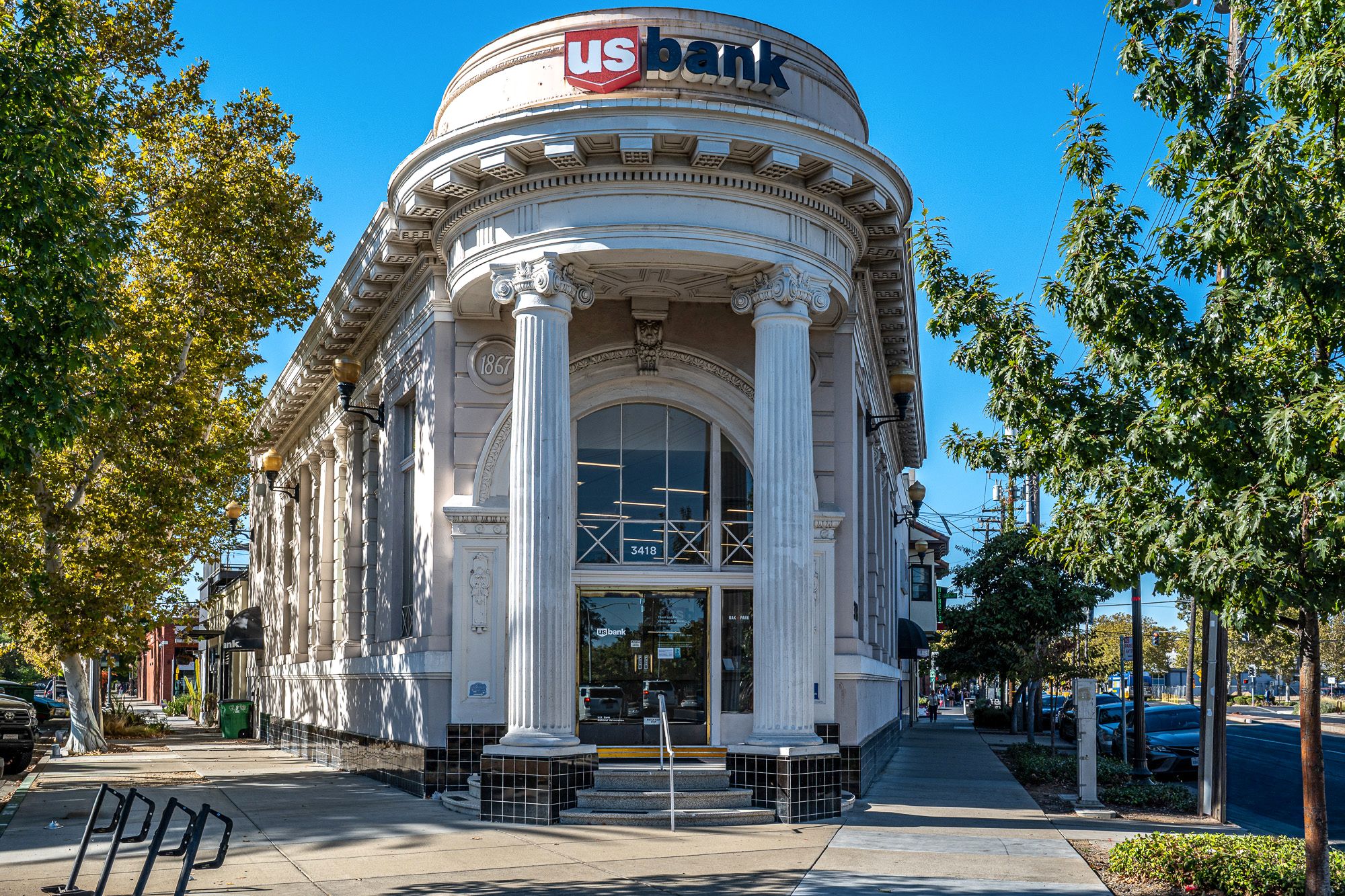 U.S. Bank branch in a classic corner building with columns and a domed roofline, surrounded by autumn trees on a sunny day.
