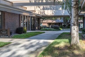 Brick commercial office building in Sacramento's Sierra Oaks business district, featuring a landscaped courtyard, covered walkway, and matur