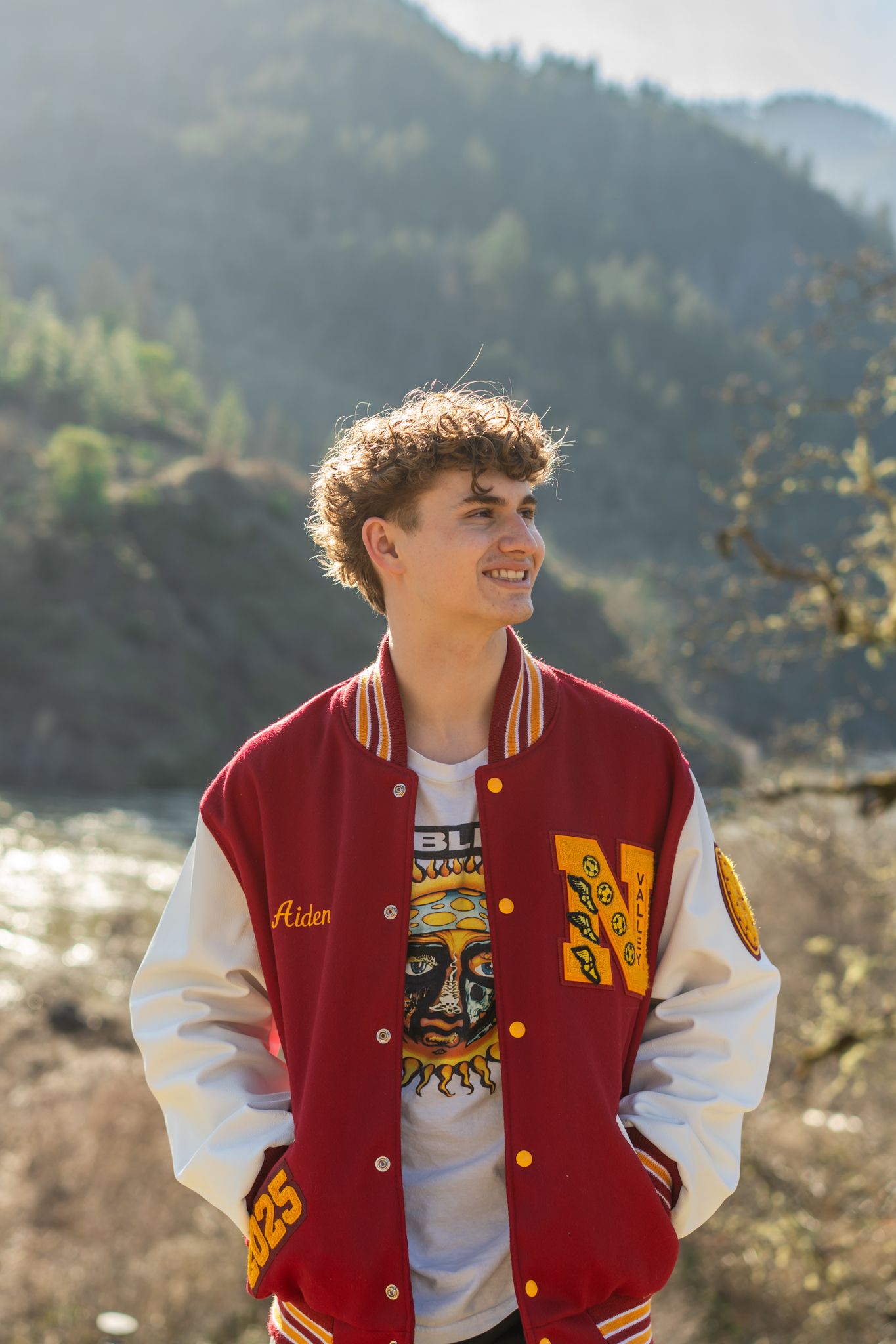 senior portrait of a young man in his letterman's jacket by the Rogue River in Southern Oregon
