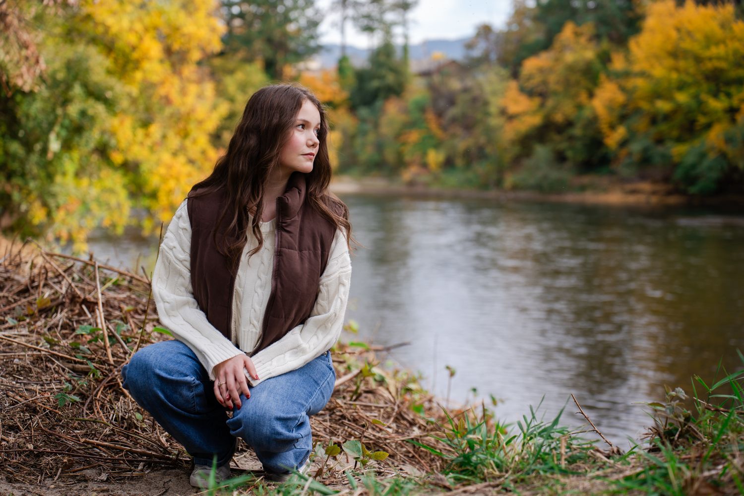 senior portrait of a girl in a sweater by the Rogue River during autumn