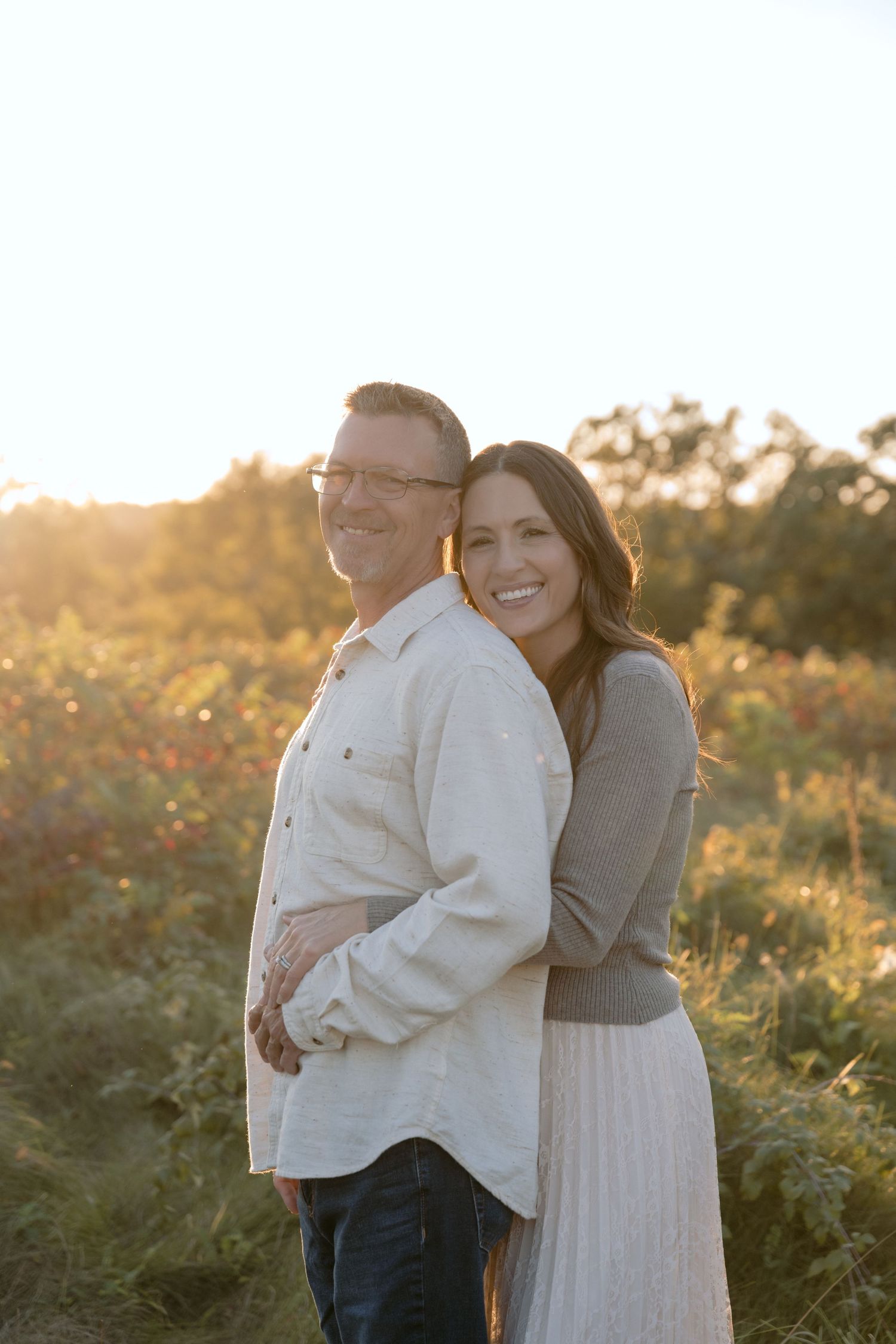 portrait of parents with the sunset glowing behind them during fall family portrait session in hudson wisconsin