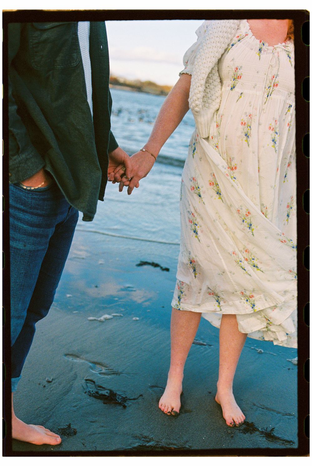 Detail of couple holding hands during a maternity shoot with 35mm film on the beach in South Portland, Maine.