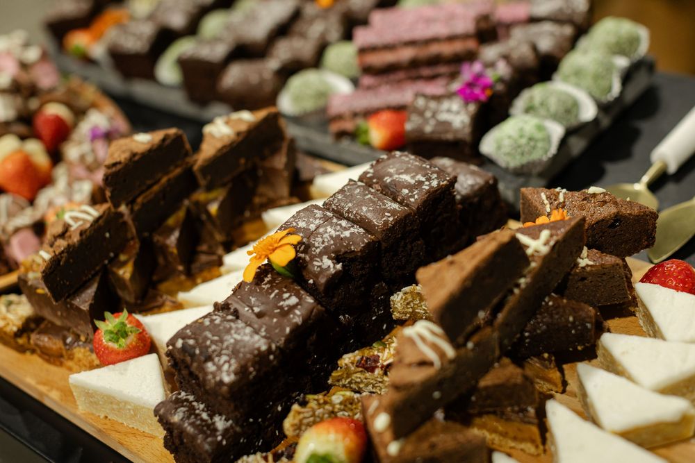 Assorted chocolate brownies and desserts arranged on wooden serving boards.