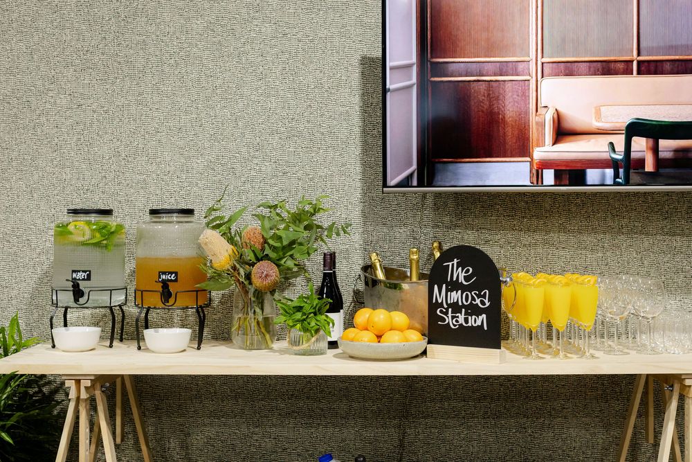 Mimosa station with yellow drinks, champagne, and fresh fruit centerpiece.