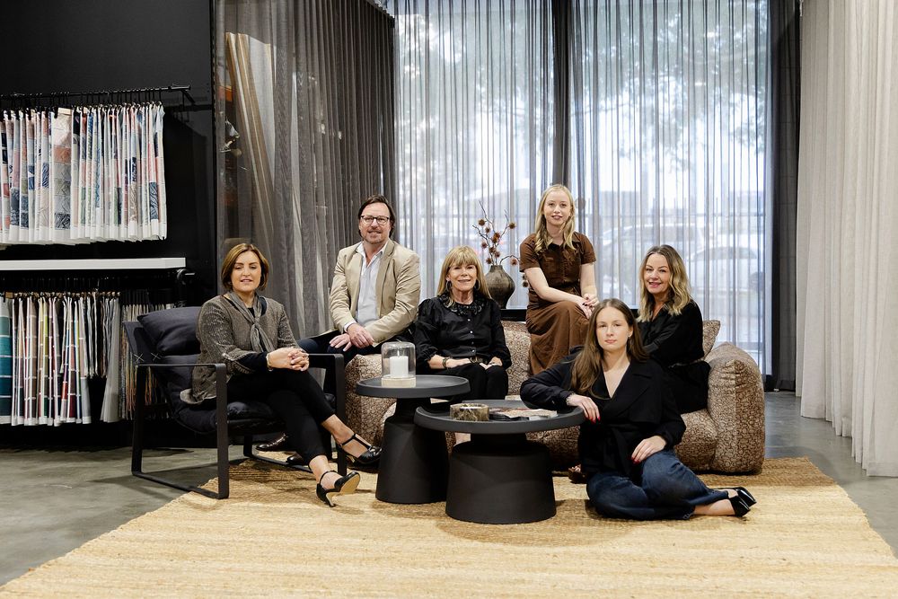 Group of six interior design professionals posing in a stylish showroom.