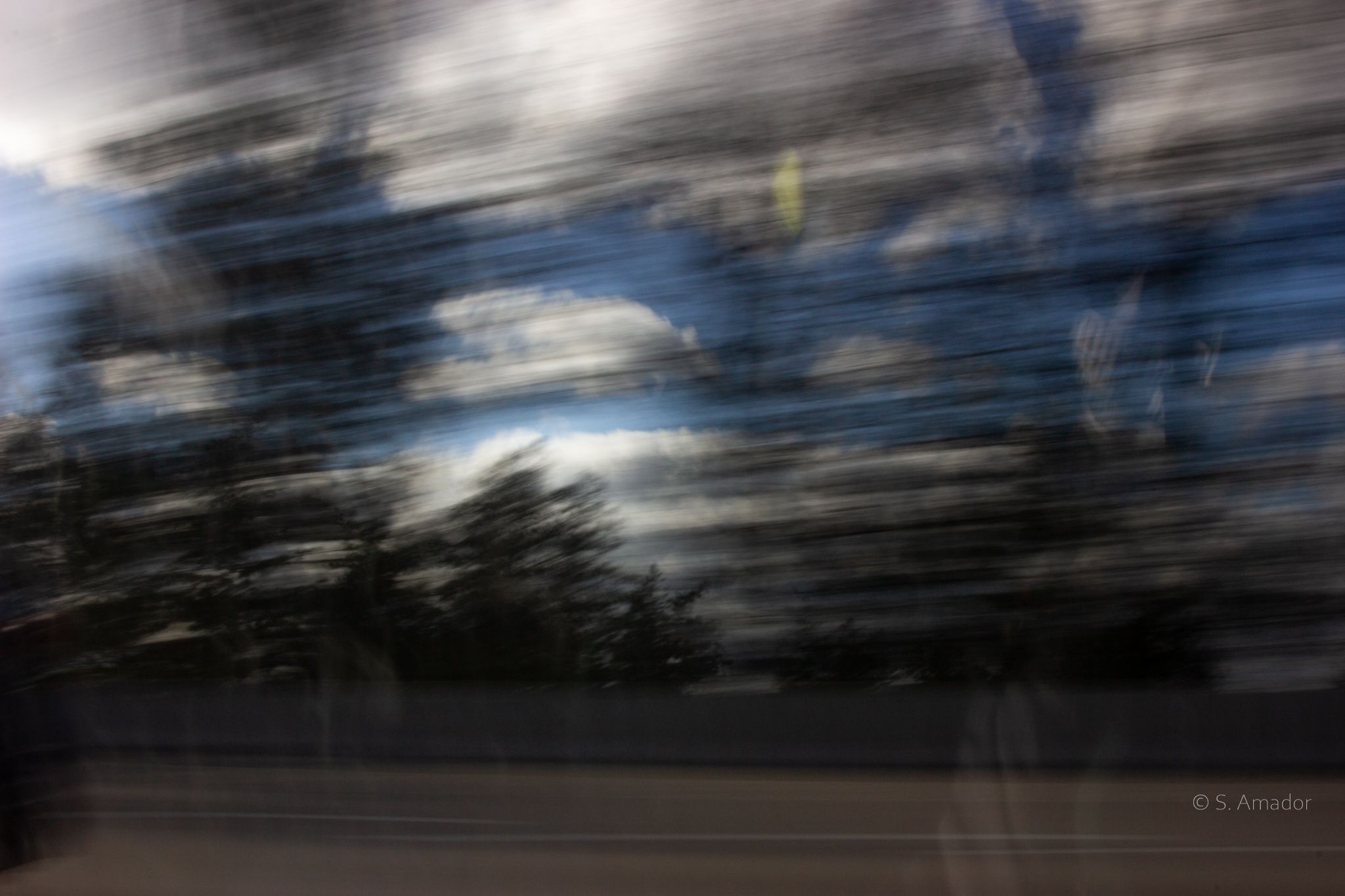 Abstract motion blur photograph of blue sky, clouds, and trees creating a dreamy effect.