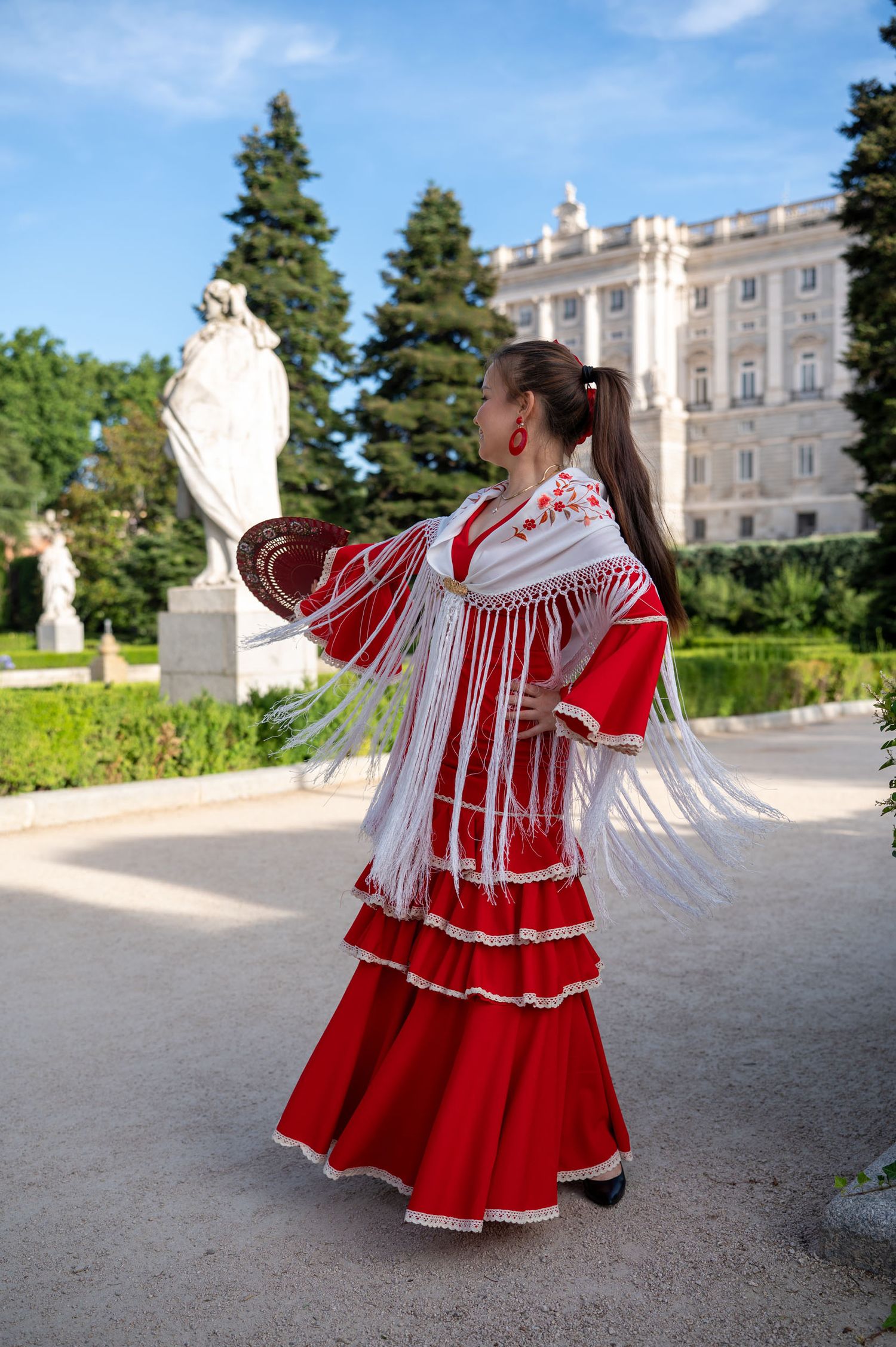 A flowing blue dress creates an ethereal silhouette against the stunning backdrop of Madrid's Almudena Cathedral at sunset.