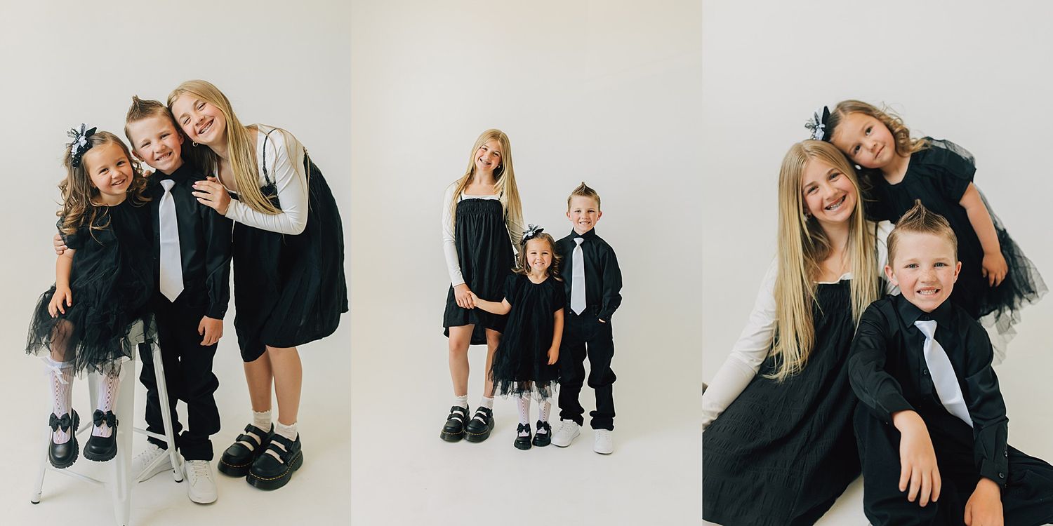 Three children in matching black formal outfits posing together in a bright white studio setting.