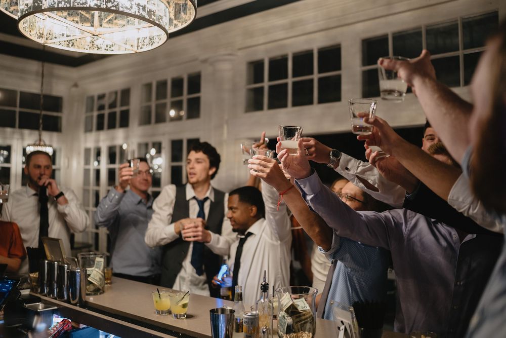 Group of people raising glasses in a toast at an elegant bar during a celebratory event.