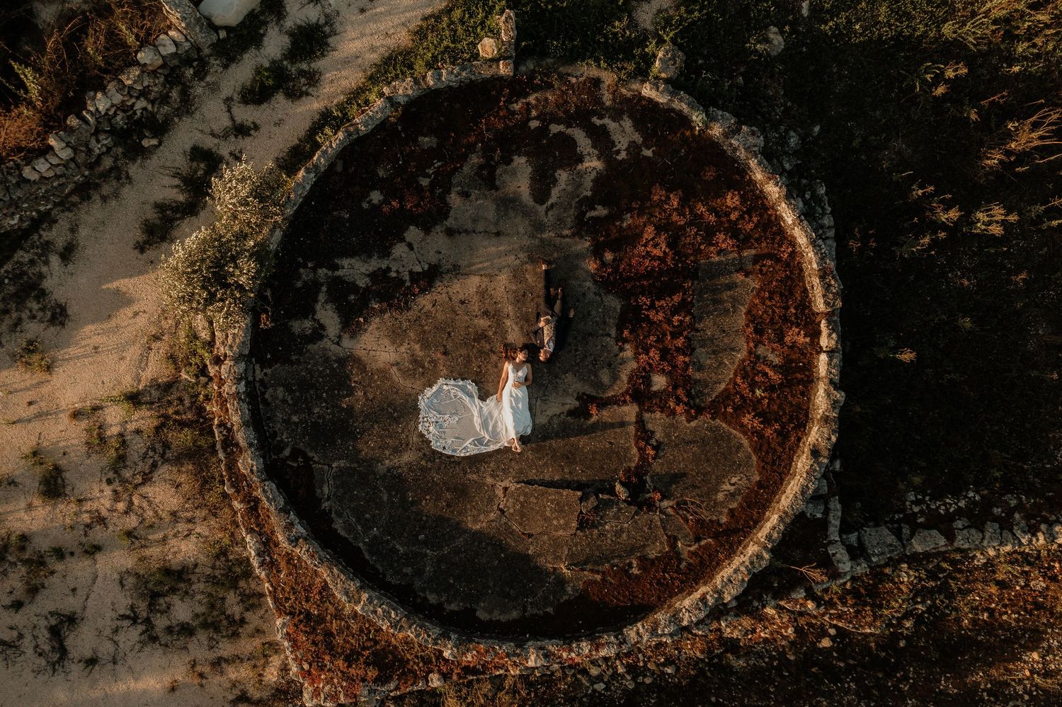 Aerial view of a massive circular earthwork or archaeological site surrounded by trees in autumn colors.