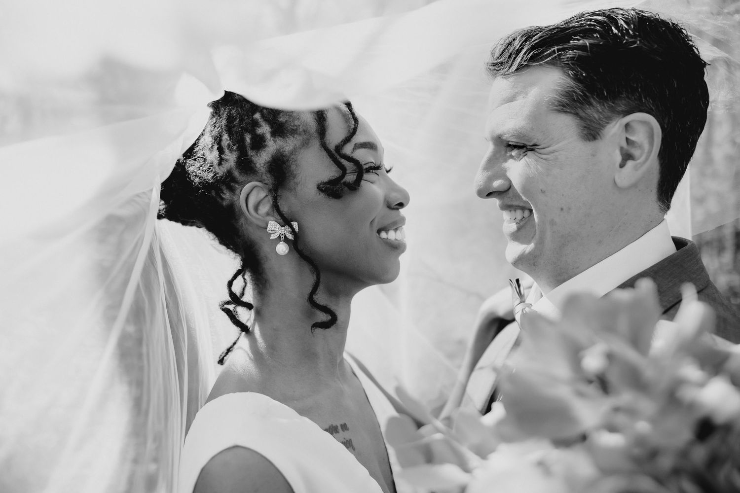 Happy young couple smiling and embracing outdoors, woman hugging man from behind in a warm, affectionate pose.