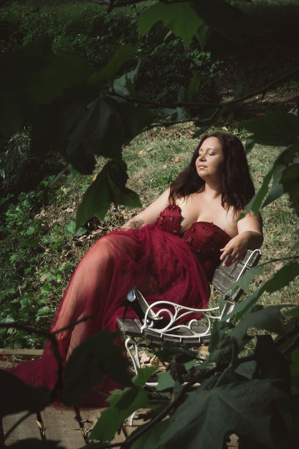 Portrait féminin dans un jardin luxuriant, baigné par une lumière naturelle contrastée.