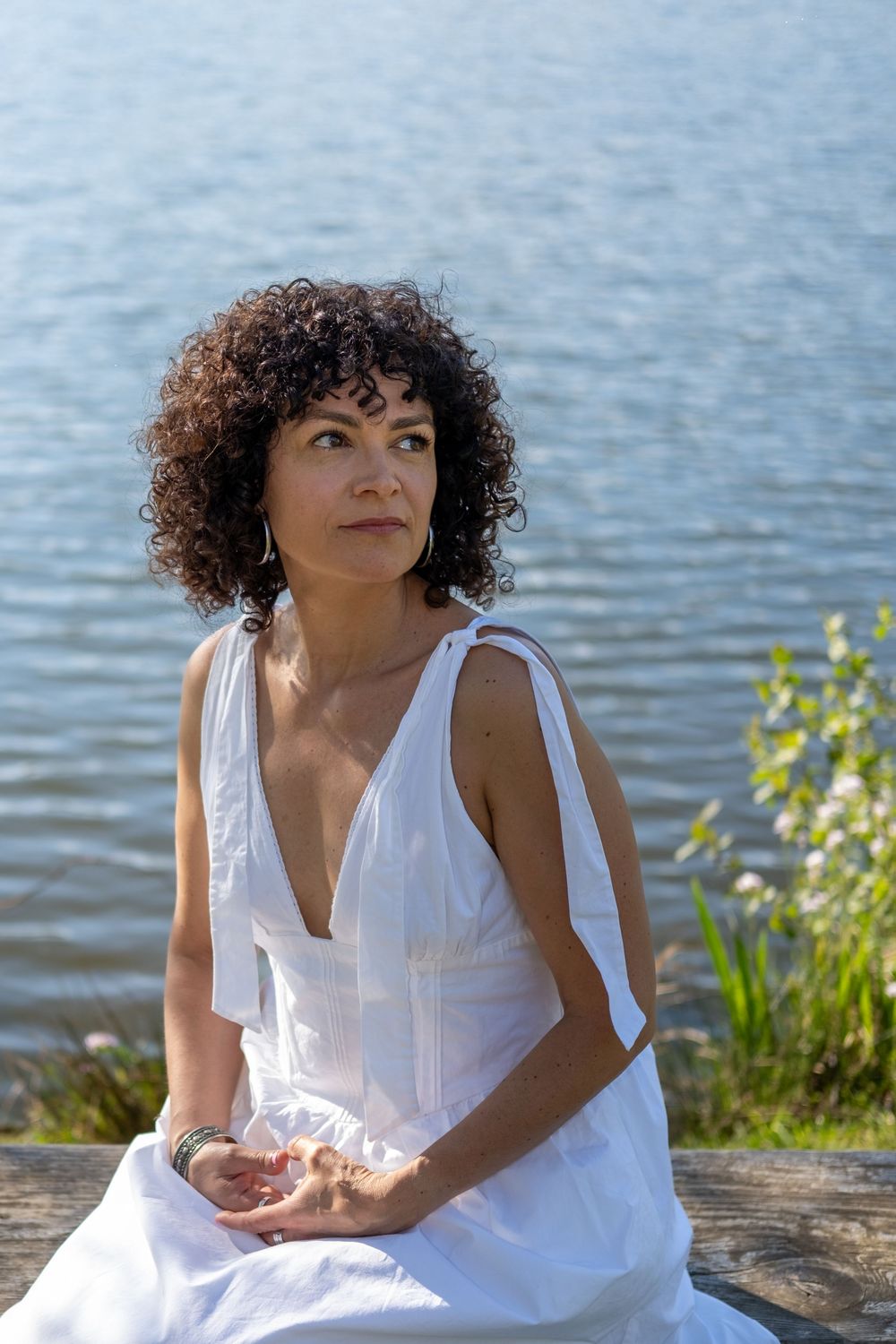 Portrait féminin assis au bord de l'eau dans un environnement naturel paisible.