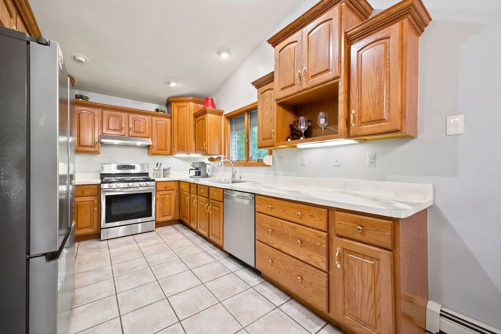 Spacious kitchen with honey oak cabinets, white marble countertops, stainless steel appliances, and light tile flooring.