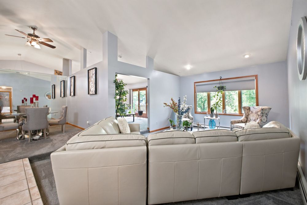 Spacious living room with light gray sectional sofa, vaulted ceilings, ceiling fan, and open floor plan with dining area.
