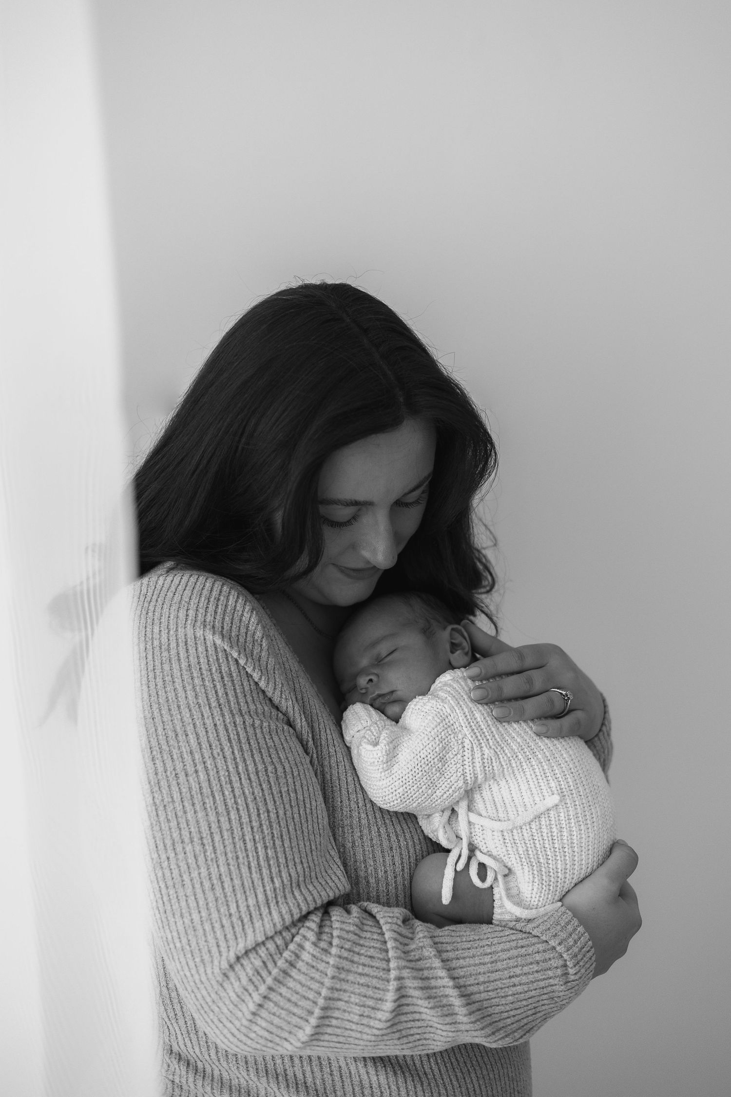 Black and white photo of a mother tenderly cradling her sleeping newborn baby newborn photographer Nottingham