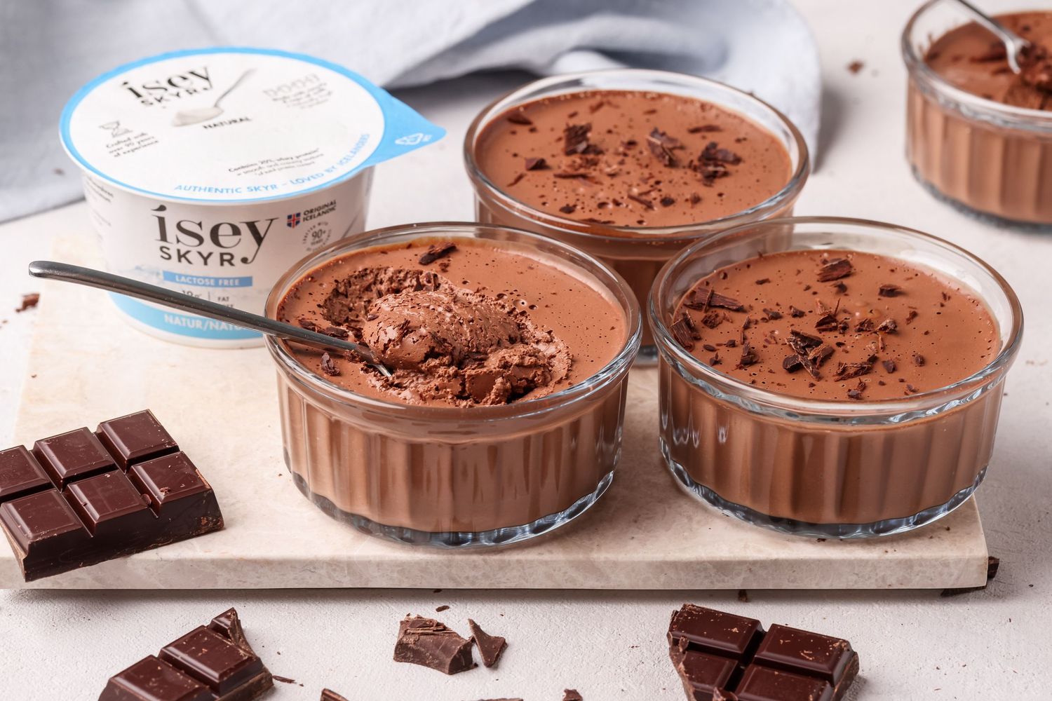 Chocolate mousse in glass ramekins on a metal tray, with Isey Skyr yogurt container nearby.