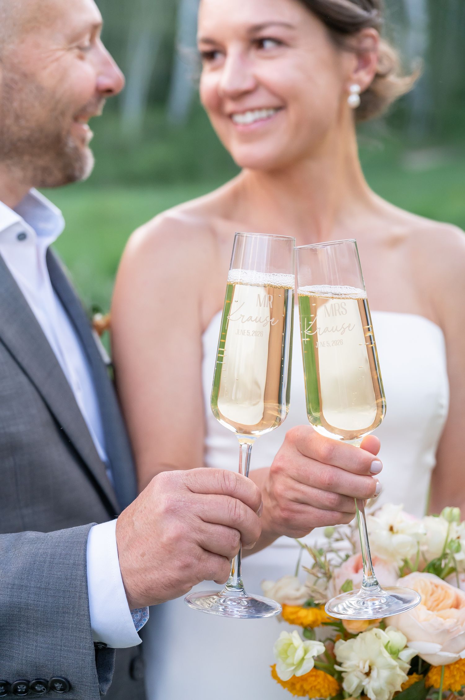 Bride and groom toasting with engraved champagne flutes at outdoor wedding celebration during Beaver Creek elopement