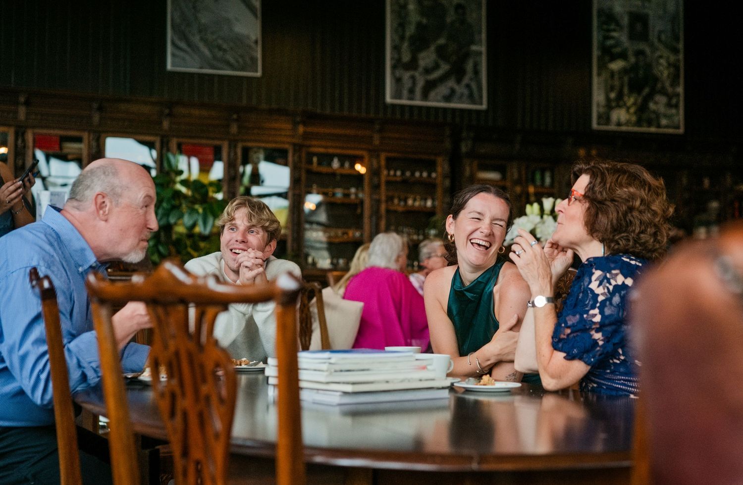 Elderly wedding guests laugh together at a beautifully decorated restaurant reception table.