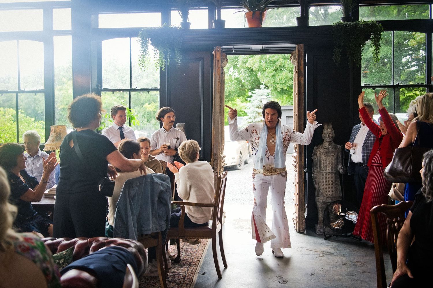 Elvis impersonator entertainer makes grand entrance at lively indoor wedding reception celebration.