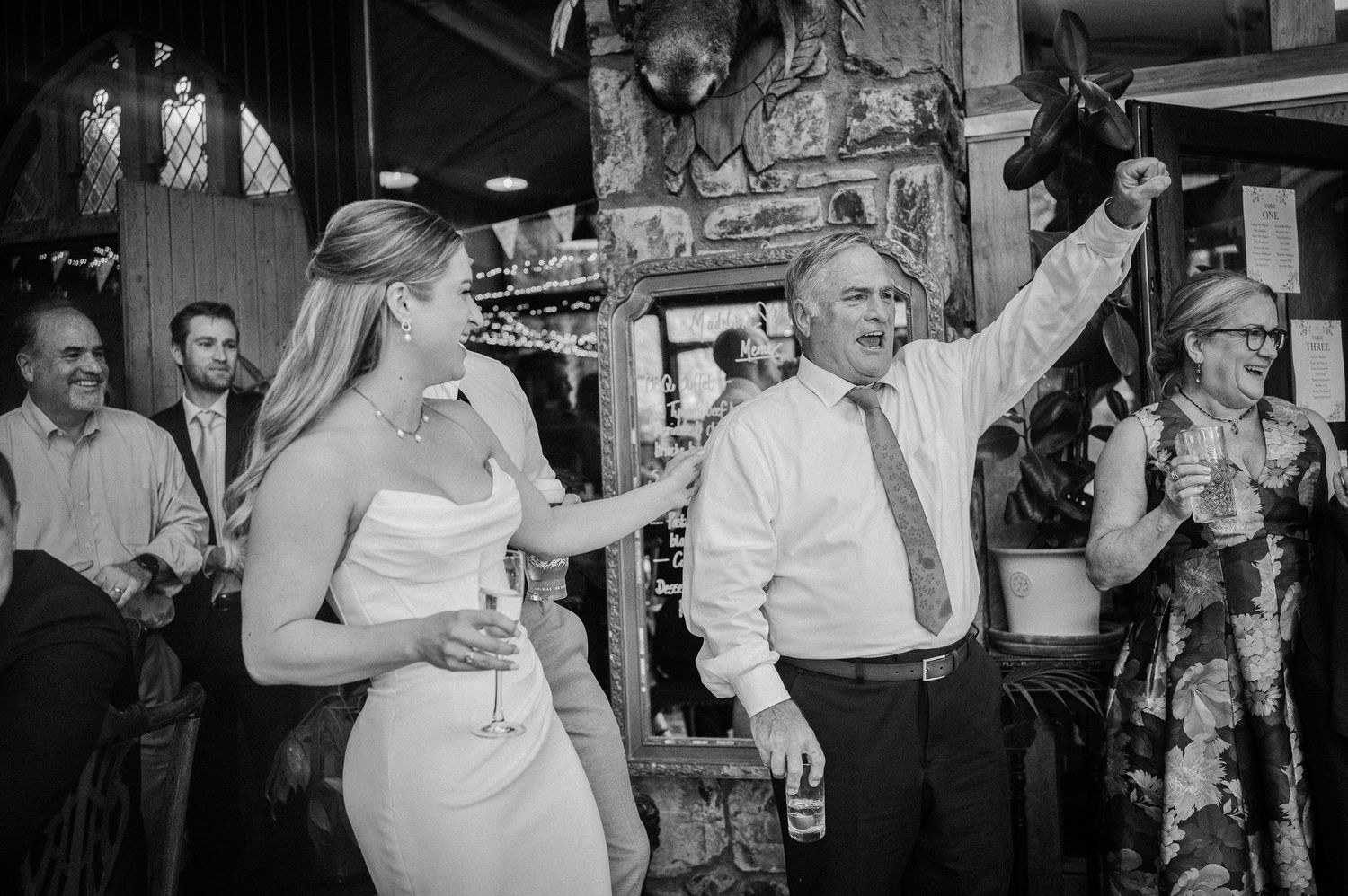 A bride and older gentleman celebrate joyfully at a lively wedding reception party.