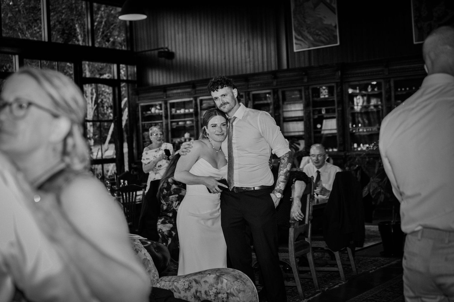 Bride and groom share a joyful moment on the dance floor surrounded by wedding guests in a rustic venue.