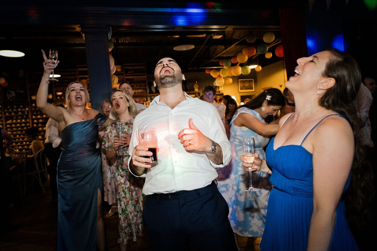 Guests dancing and celebrating joyfully at a lively wedding reception party.