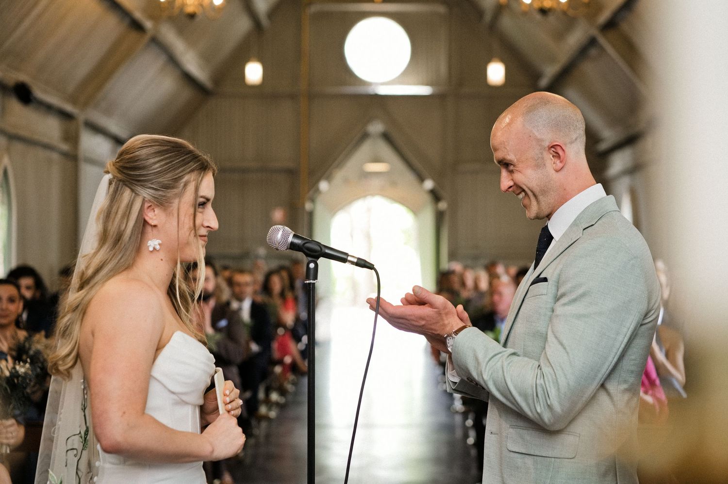 Groom reads vows to smiling bride at the altar during intimate wedding ceremony.