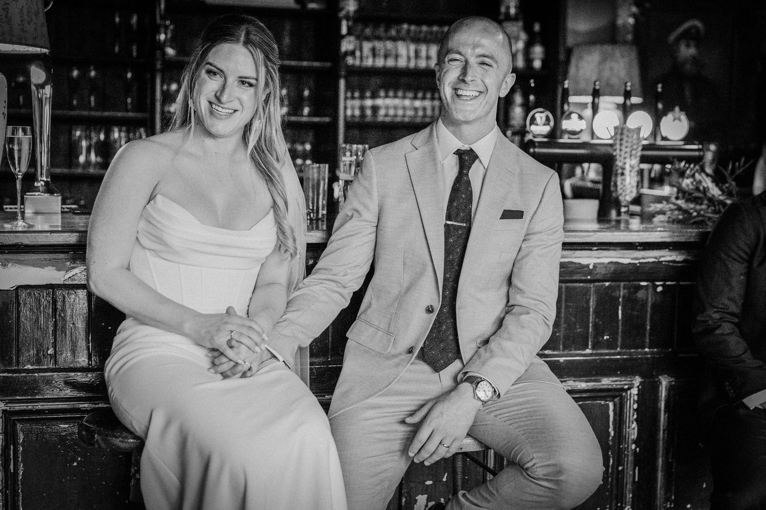 Bride and groom pose together at a bar in black and white wedding portrait photo.