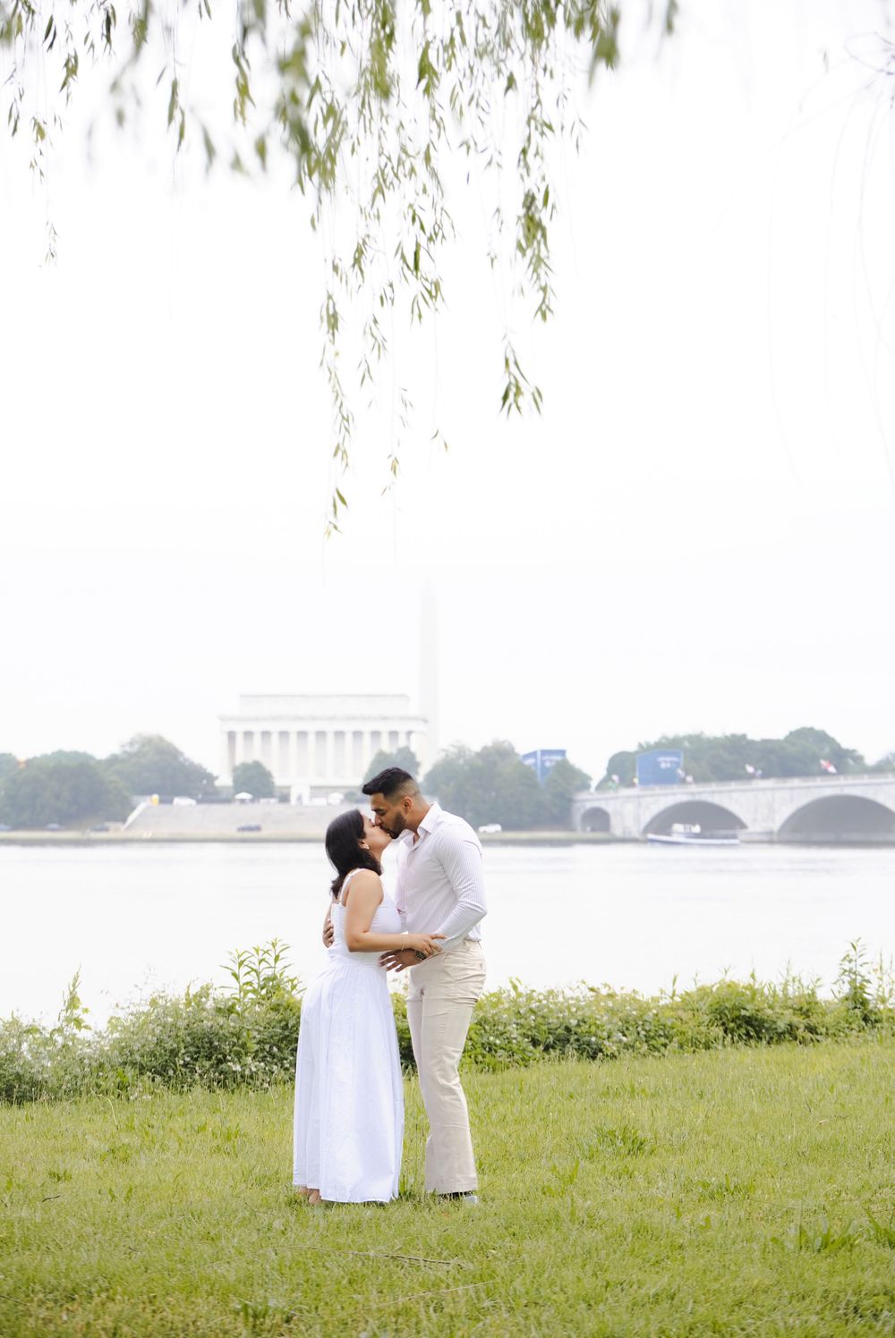 Couple in white embracing by the Potomac River with the Lincoln Memorial in the background, Washington DC.