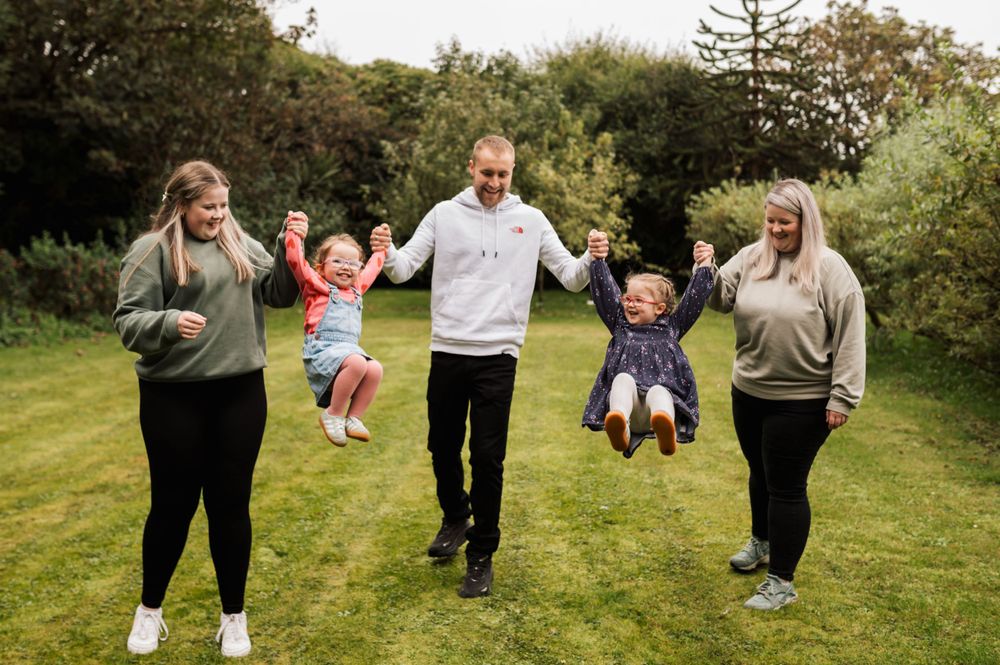 Joyful group in matching sweatshirts playing together on green grass in a backyard setting.