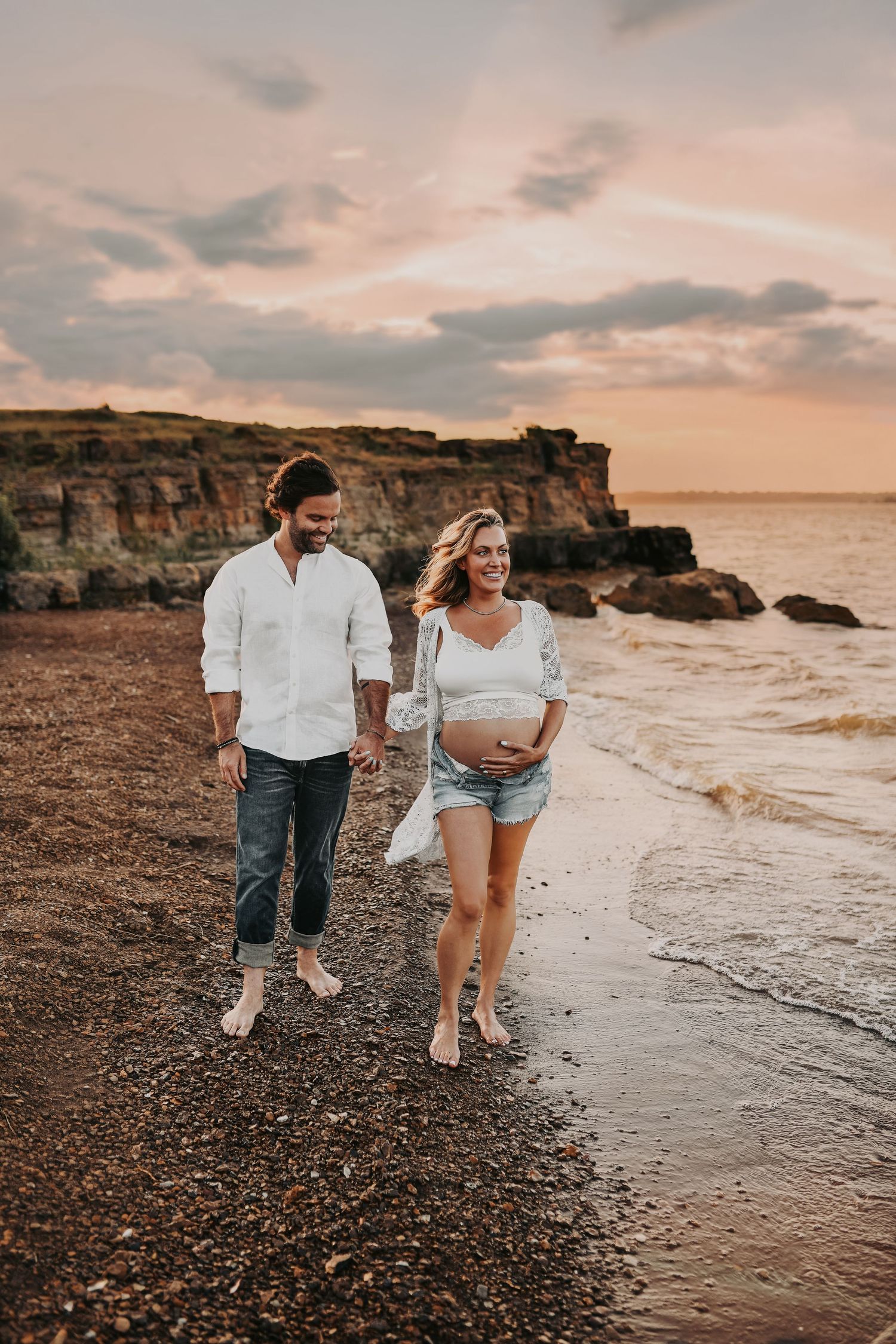 Couple laughing during maternity photos by the water