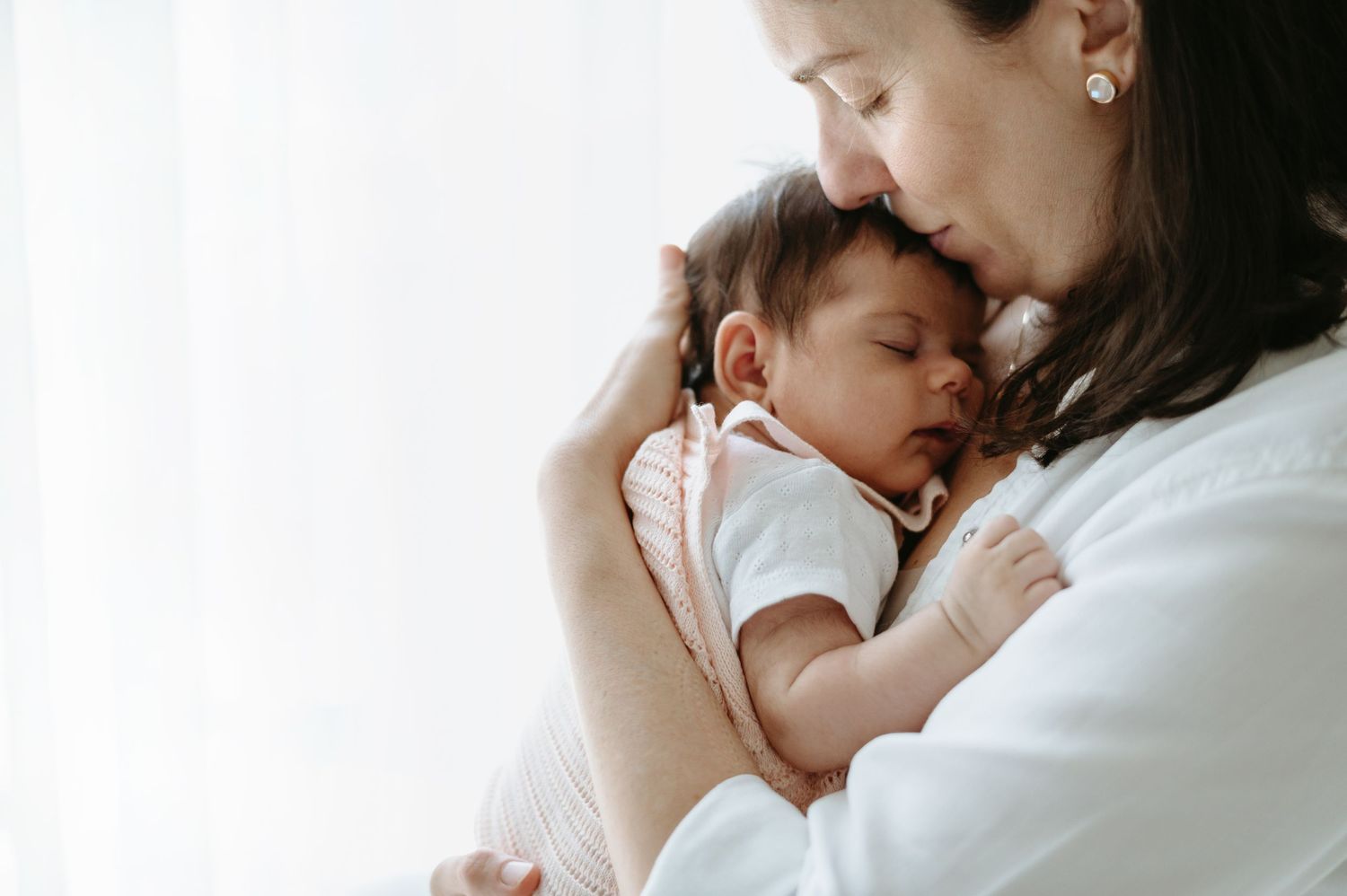 Group shares joyful moment with newborn baby on white blanket.